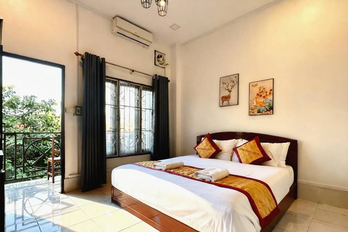 Een hotelkamer met een groot bed, een balkon en uitzicht op groen.