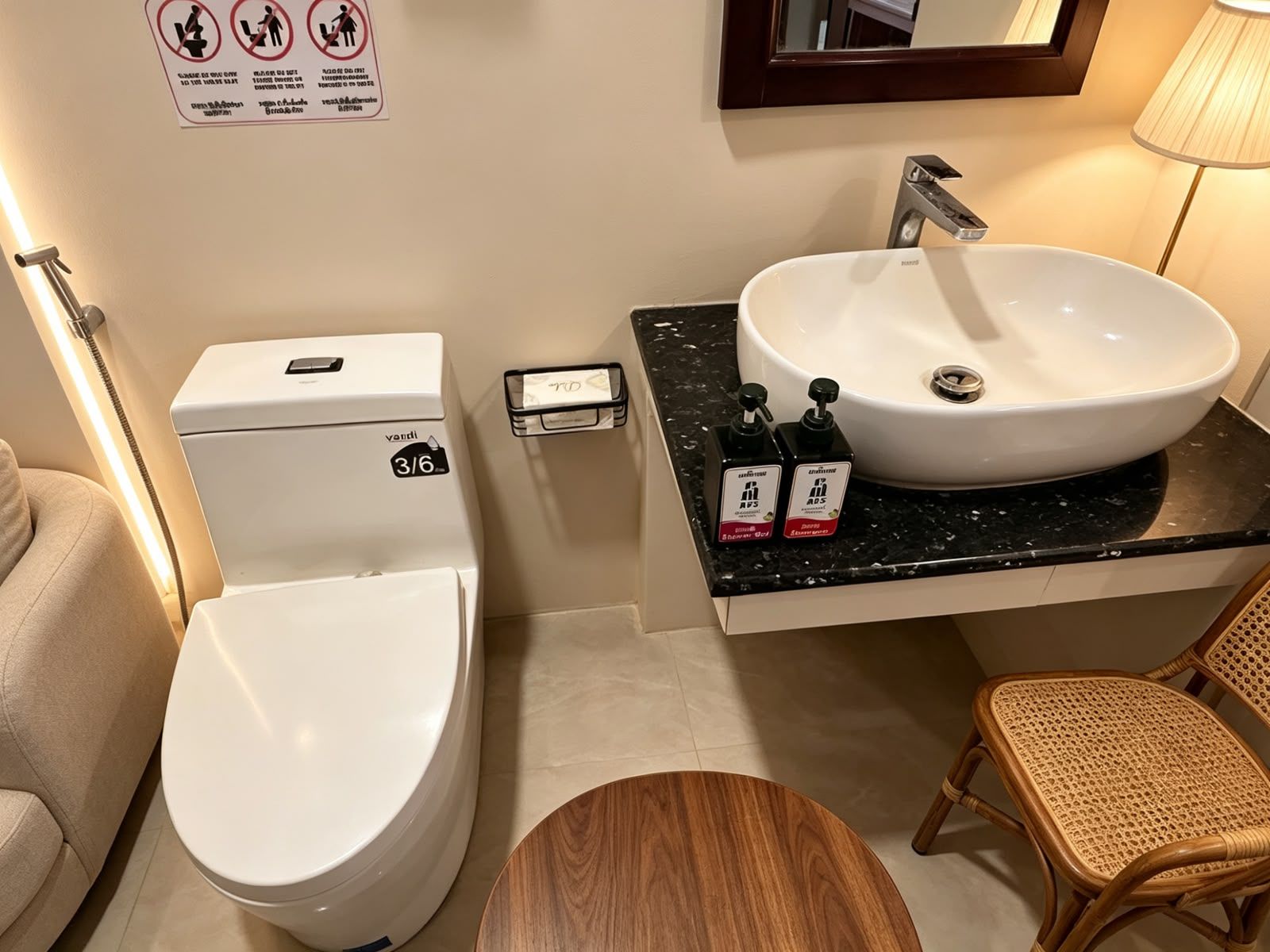 Un baño con inodoro, lavabo, espejo y dispensador de gel antibacterial.
