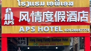 La entrada del Hotel APS, con fachada roja y amarilla, un número de contacto y un letrero que indica que es un hotel boutique familiar.