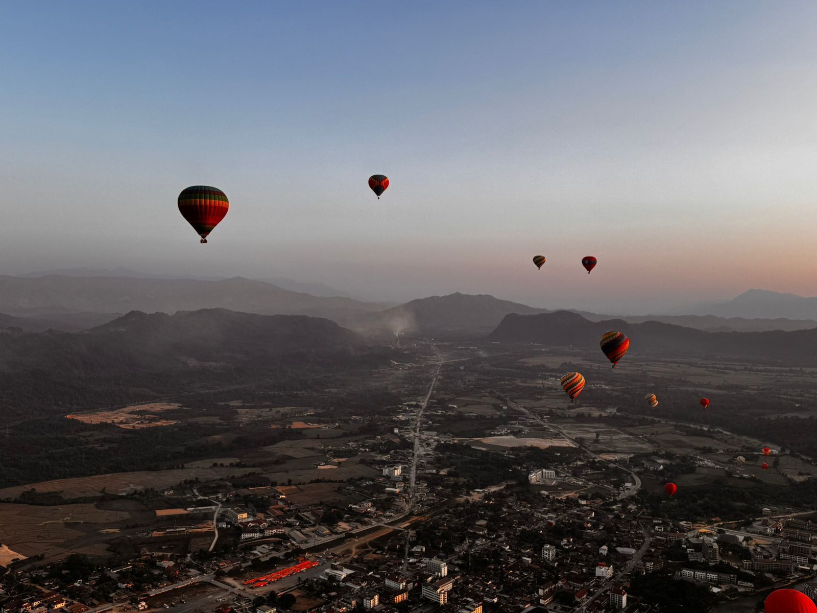 Une vue d’une ville avec des montgolfières dans le ciel.
