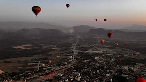 Un paisaje urbano con globos aerostáticos en el cielo.