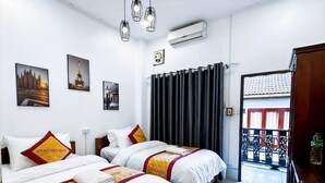 Habitación de hotel con dos camas, un ventanal con cortinas y obras de arte en las paredes.