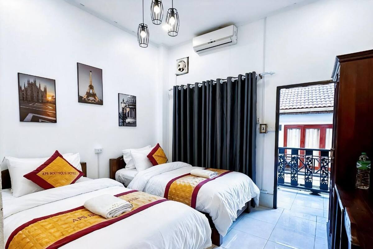 Een hotelkamer met twee bedden, een uitzicht op het balkon en kunstwerken aan de muur.