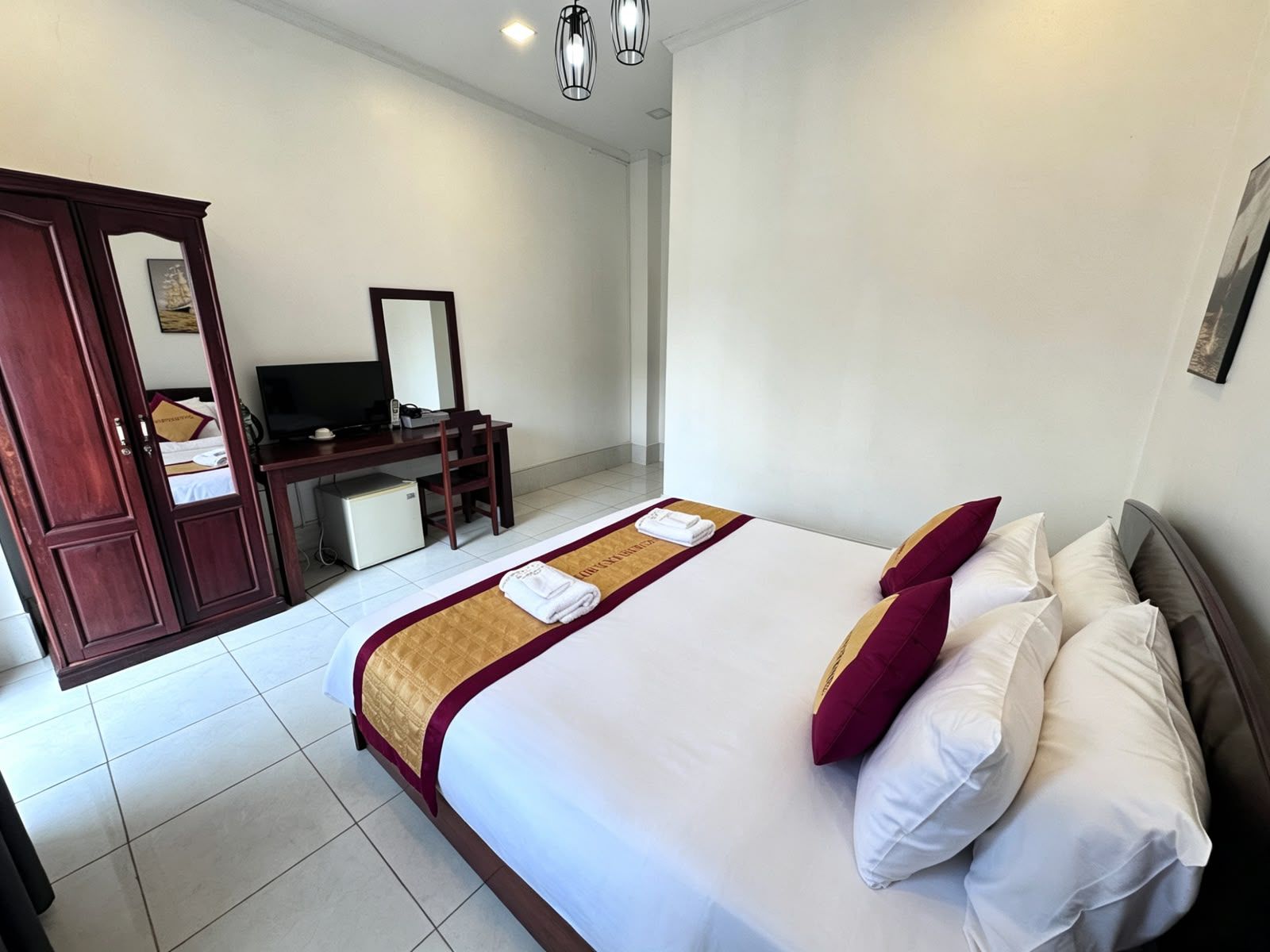 Een hotelkamer met een bed, een bureau, een televisietoestel en een kledingkast.