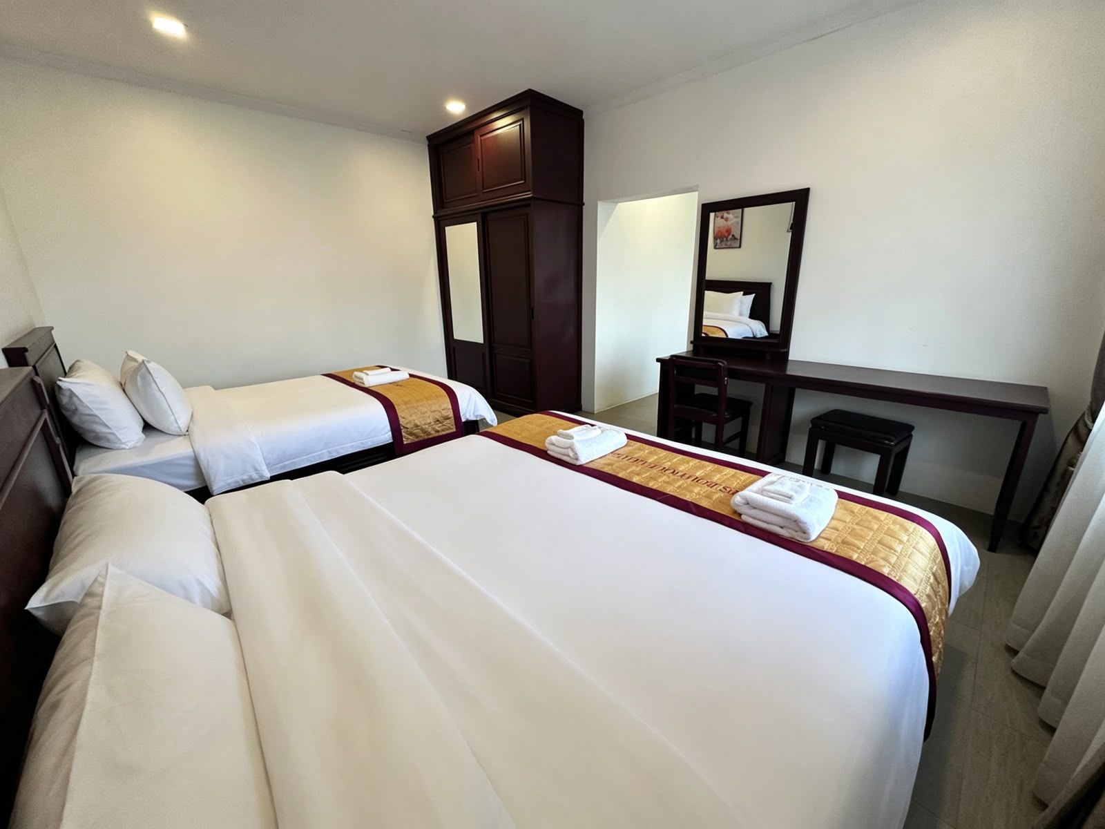 Habitación de hotel con dos camas, un escritorio, una silla y un espejo.