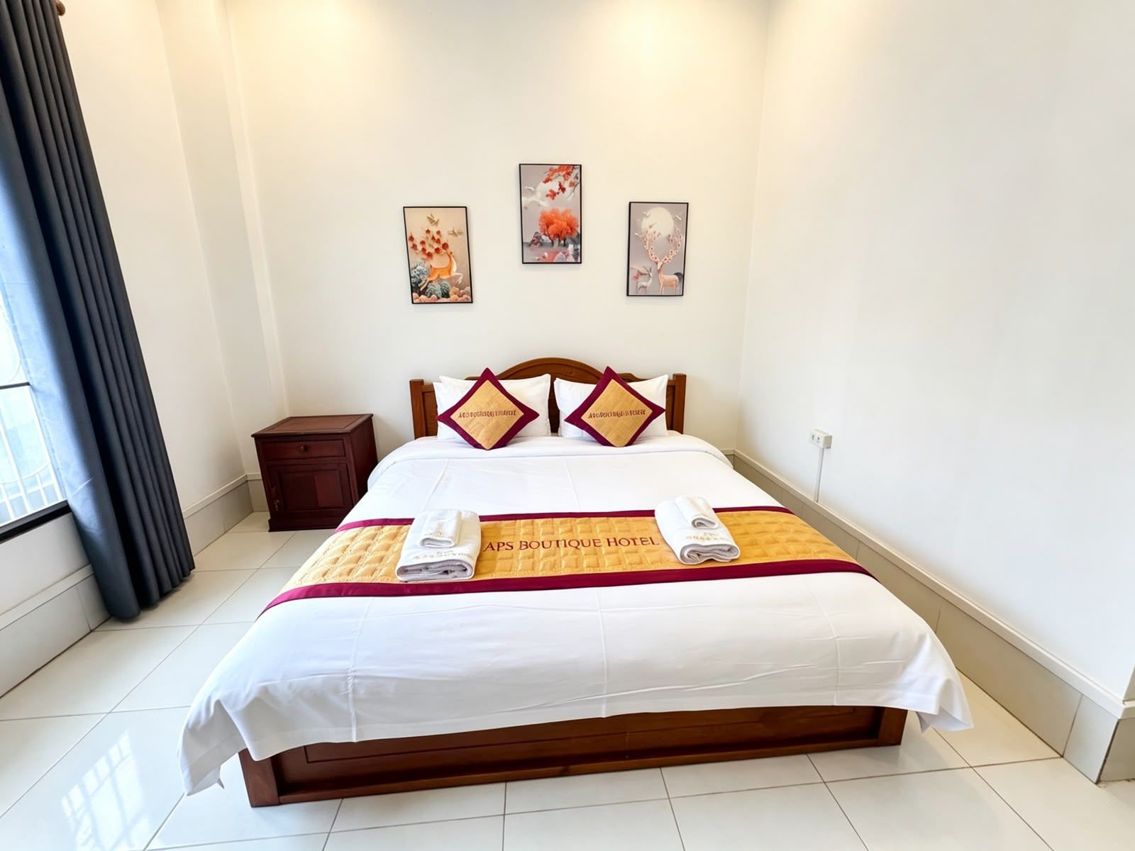 A hotel room with a bed, a nightstand, and three wall-mounted artworks.