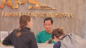 Un mostrador de recepción en el APS Family Boutique Hotel con un fondo de madera y un código QR para el registro.