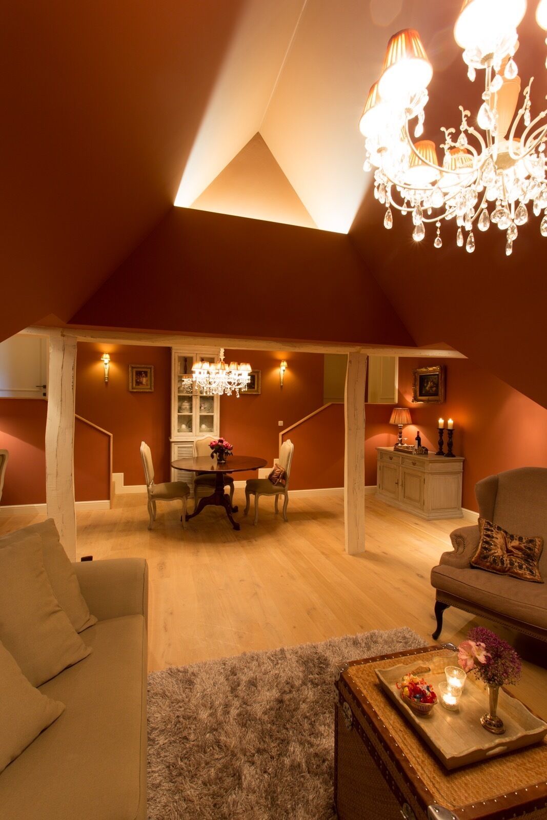 A cozy loft-style room with a dining area, a chandelier, and a fireplace.