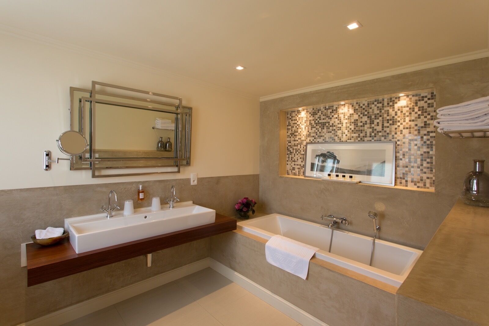 Une salle de bain moderne avec un double vasque, une grande baignoire et une cabine de douche dont le sol est recouvert de mosaïques.