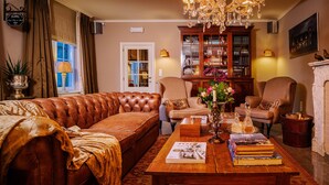 A cozy living room with a leather sofa, a wooden coffee table with books, a fireplace, and a bookshelf. - Villa Reynaert (Maaseik)