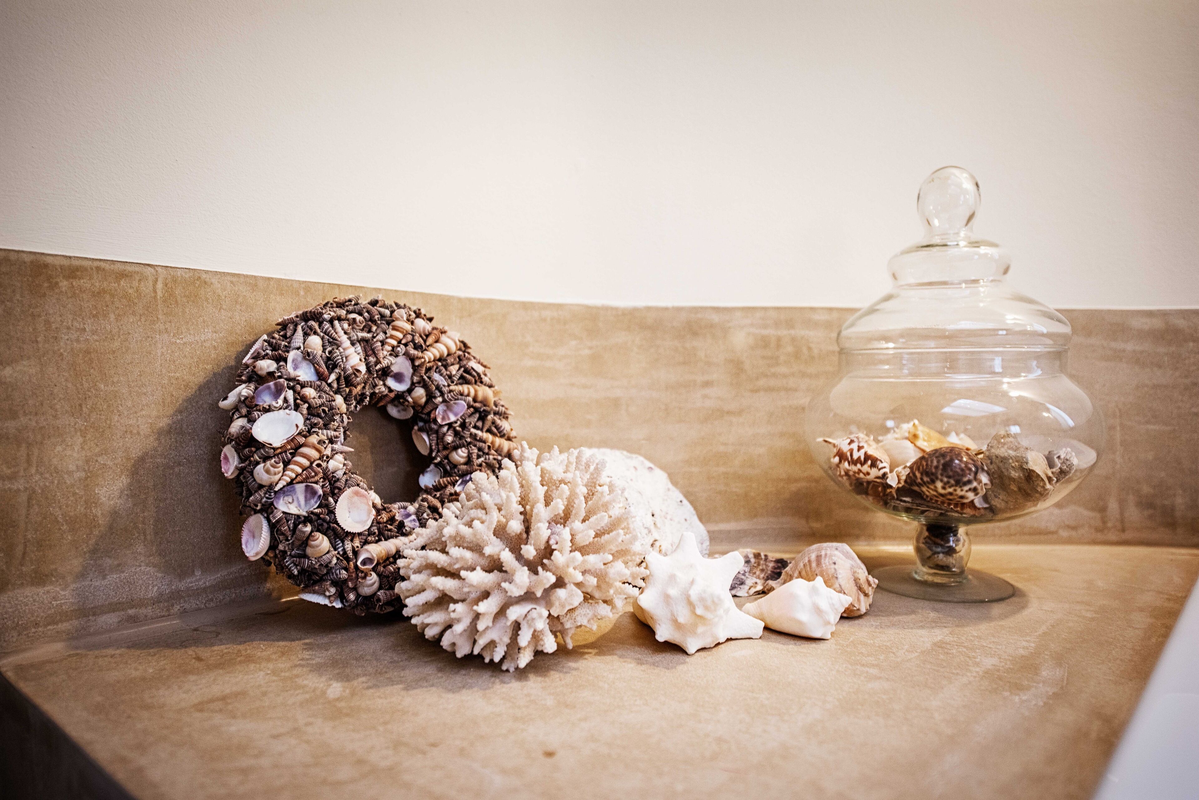 A decorative arrangement of seashells and a glass jar on a wooden surface.