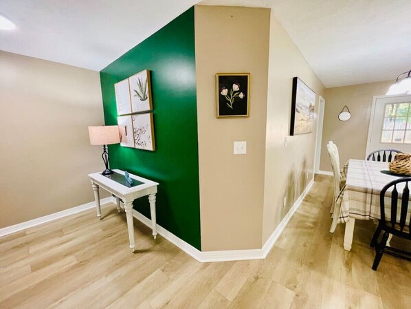 A dining area with a table and chairs, a lamp, and framed botanical prints on the wall.