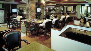 Een restaurant met houten balken, bakstenen muren en een televisiescherm waarop een programma wordt vertoond.