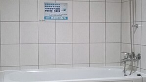Een badkamer met een bad, toilet en douche.