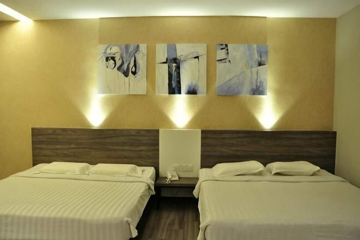 A hotel room with two beds, a wooden headboard, and three abstract paintings on the wall.