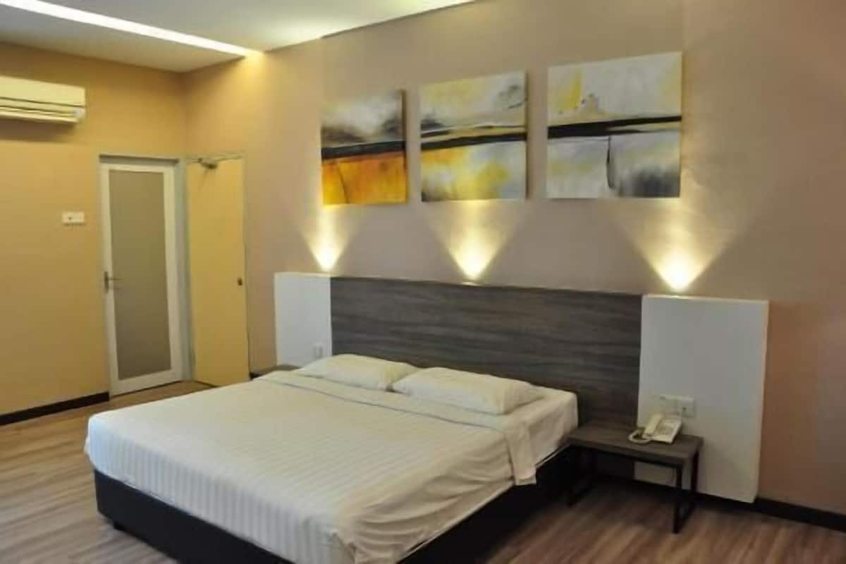 A hotel room with a bed, bedside tables, a wall-mounted phone, and abstract art.