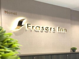 Pareda com o texto "Frasers Inn" iluminado por uma luminária.