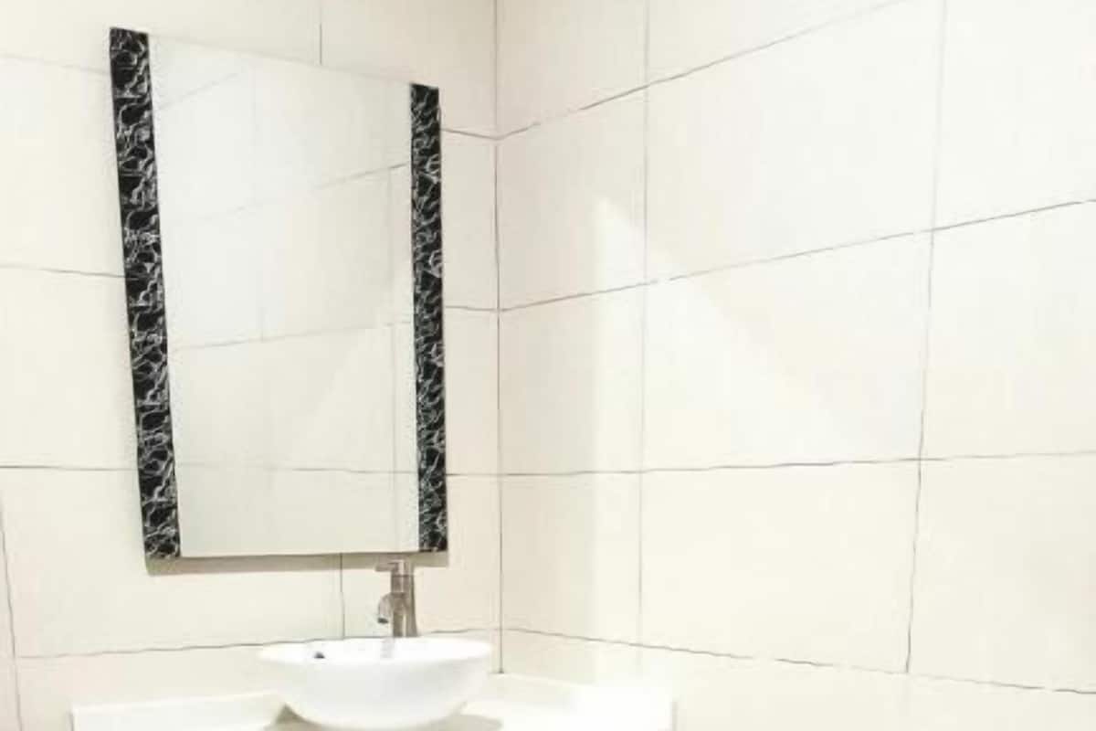 A bathroom with a white sink, a toilet, and a mirror with a black frame.