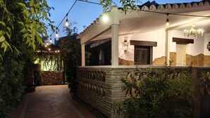 A covered outdoor area with stone walls, a tiled floor, and string lights.