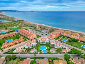 A coastal resort with multiple buildings, swimming pools, and a beach.