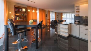 Una cocina moderna con comedor, estantería y cafetera.