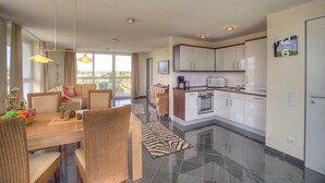 A modern apartment with a dining area, kitchen, and living space.