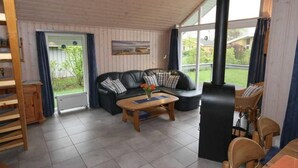 Un salon chaleureux avec un canapé en cuir noir, une table basse en bois et un poêle à bois noir.
