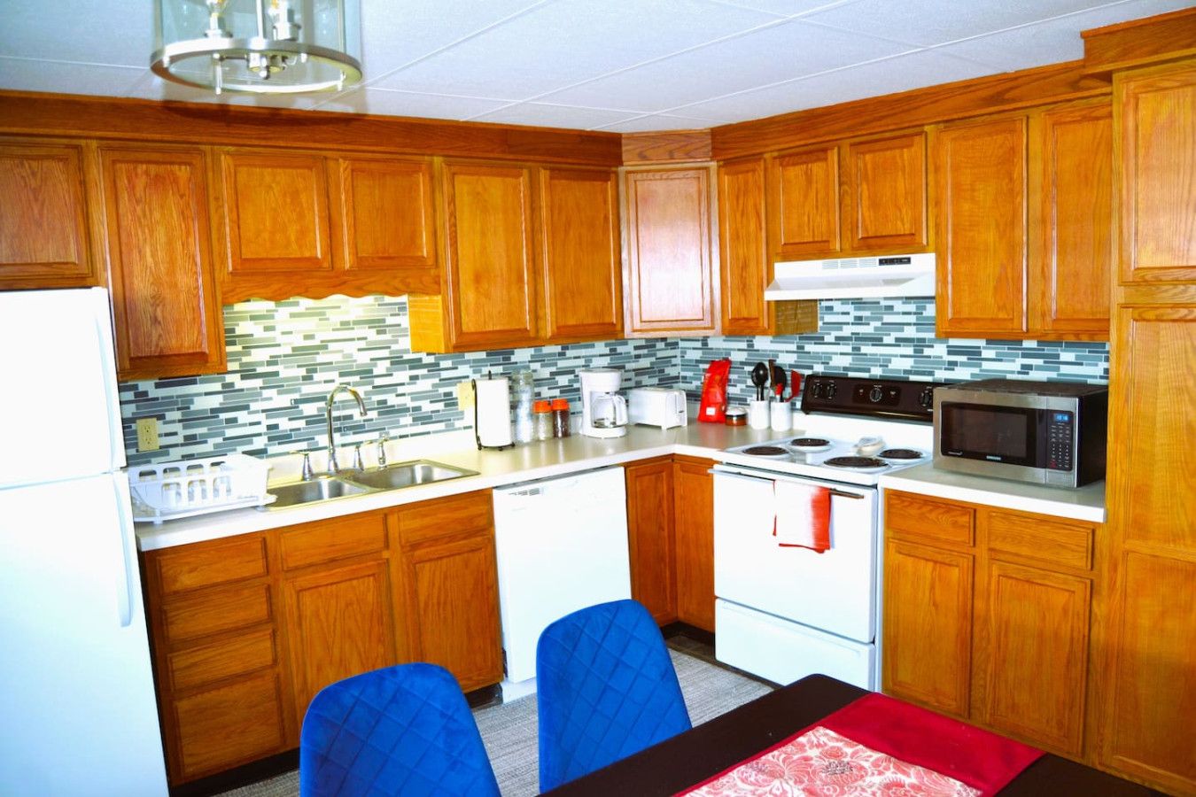 A compact kitchen with wooden cabinets, a white stove, a microwave, and a sink.