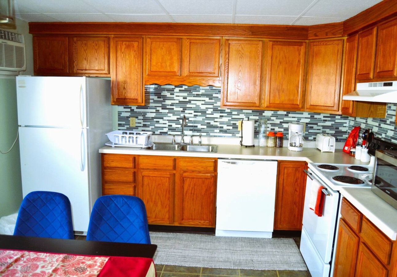 A compact kitchen with wooden cabinets, a white refrigerator, a sink, and a stove.