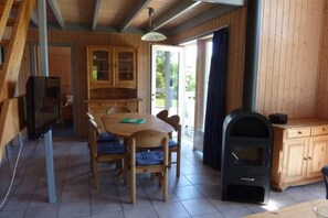 A wooden interior with a dining table, chairs, a built-in stove, and a kitchen area with cabinets. - Ferienhaus im Ferienpark Mueritz (Rechlin)