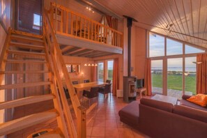 Step into this cabin's spacious interior, featuring a high ceiling and wooden beams, with a cozy seating area and dining space.