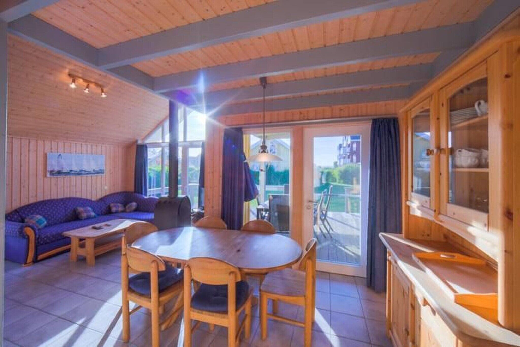A cozy wooden interior with a dining area, sofa, and kitchen cabinets.