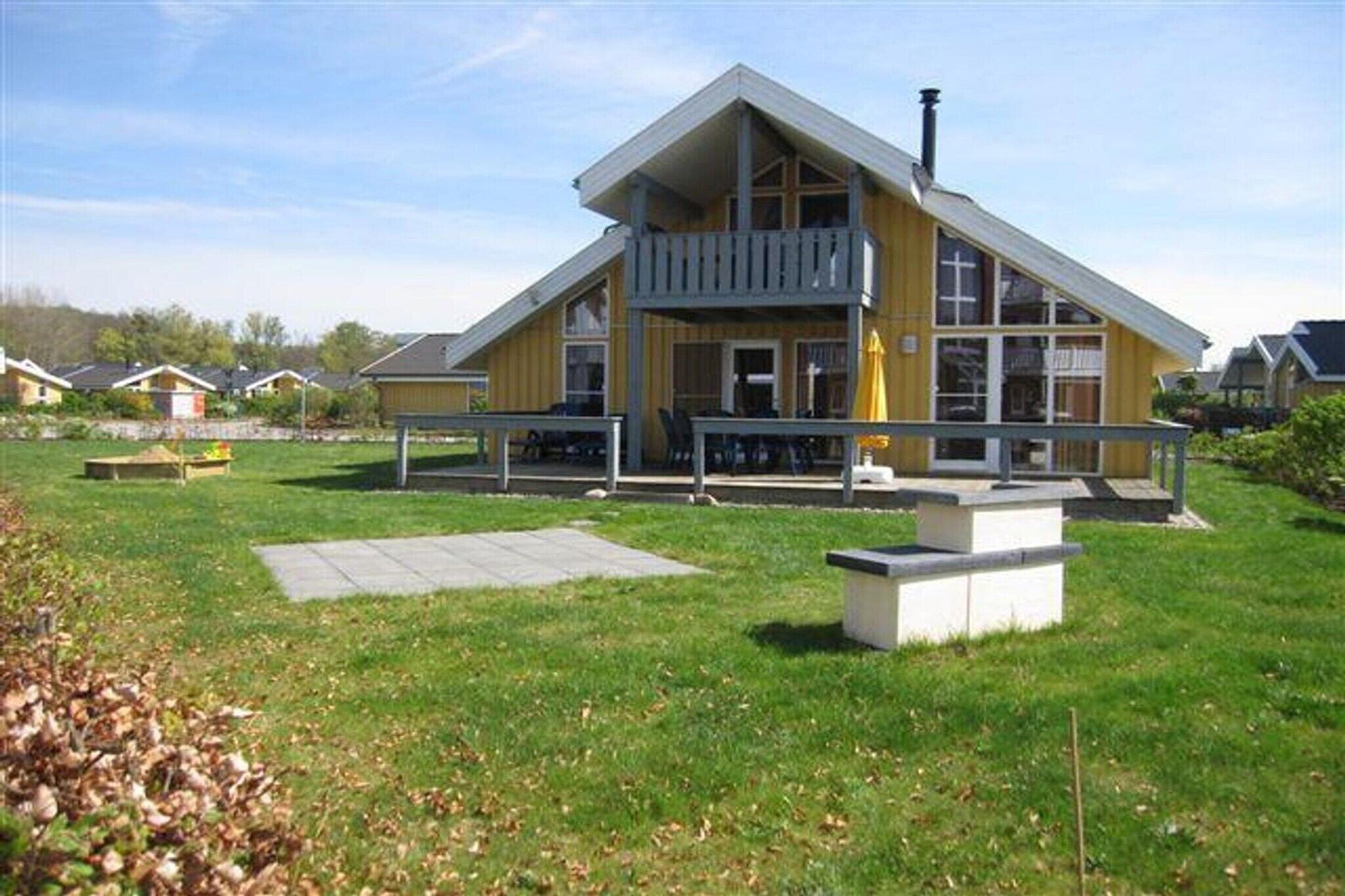 Un bâtiment jaune doté d’un balcon, d’une zone pavée et d’un petit jardin.