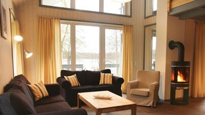 A cozy living room with a fireplace, two sofas, a coffee table, and a chair.