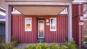 A red wooden building with two windows and a door, featuring a small porch and a mailbox.