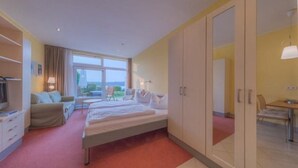 Een hotelkamer met een bed, een bureau, een stoel, een televisie en een kledingkast.