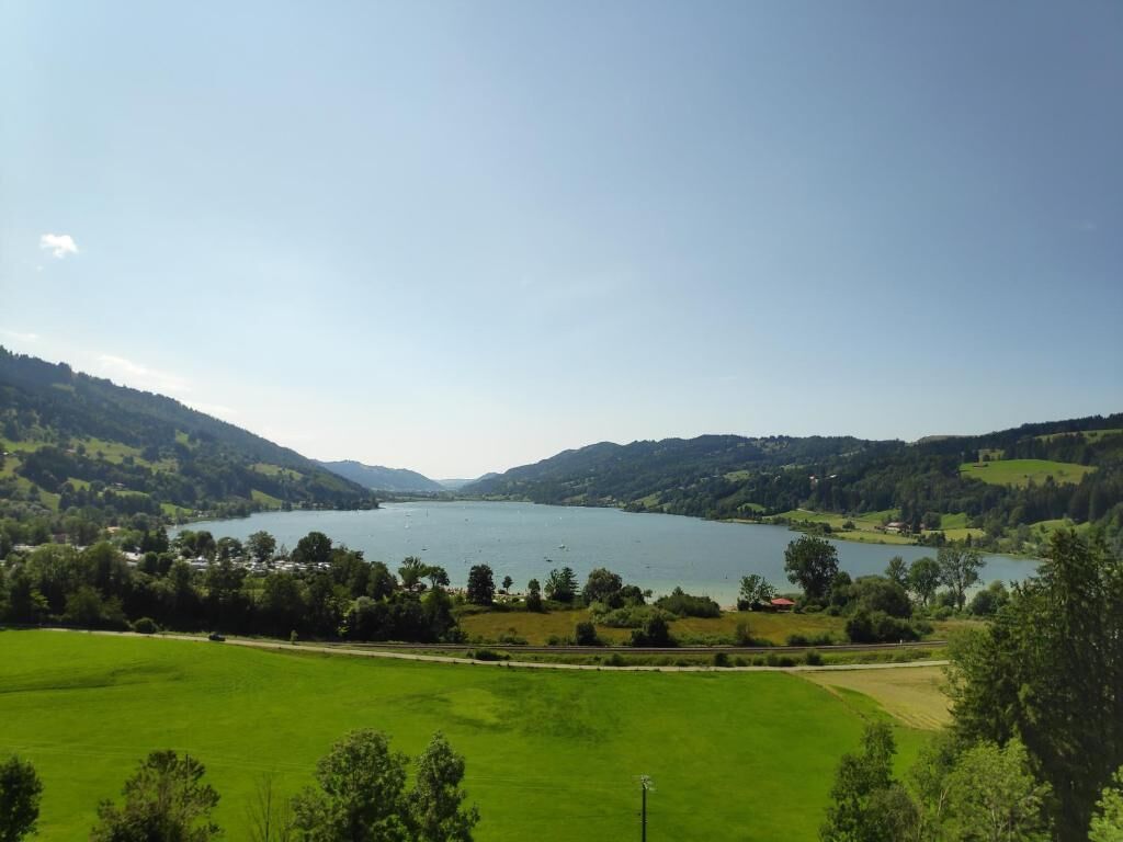 Ein See, umgeben von grünen Hügeln und einem klaren Himmel.