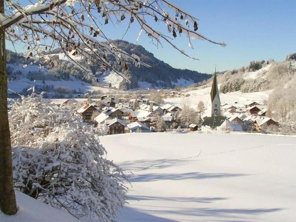 Ein schneebedecktes Dorf mit traditionellen Häusern und einer Kirche.