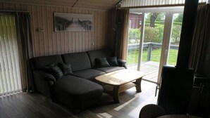 Una habitación acogedora con un sofá modular, una mesa de centro de madera y vistas al exterior a través de un ventanal corredero.