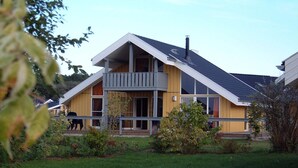 Ein modernes, zweistöckiges Haus mit Balkon, Schornstein und gepflegtem Rasen.
