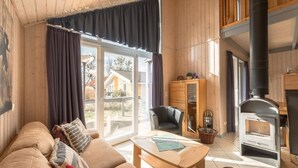 A cozy living room with a sofa, a table, a chair, a cabinet, and a fireplace. - Ferienhaus im Ferienpark Mueritz (Rechlin)