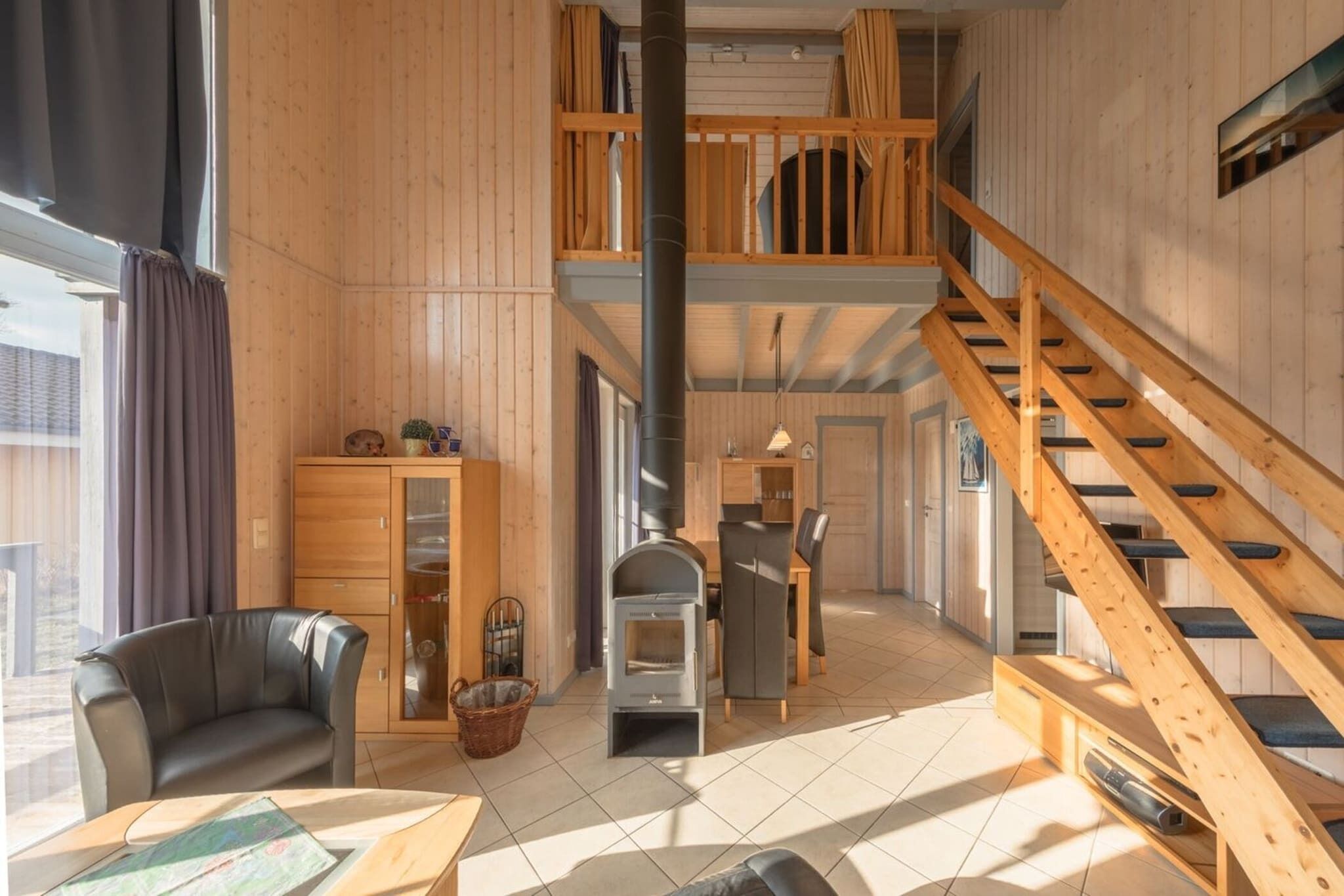 A spacious room with a wooden interior, a fireplace, a dining area, and a staircase.