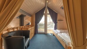 A cozy cabin room with a bed, a sofa, and a wooden ceiling. - Ferienhaus im Ferienpark Mueritz (Rechlin)
