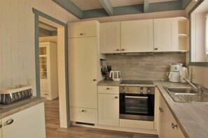 A compact kitchen with white cabinets, a built-in oven, and a sink. - skandinavisches Ferienhaus in Rechlin (Rechlin)