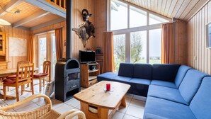 A cozy cabin interior with a wooden dining area, a blue sofa, and a stone wall decoration. - Ferienhaus im Ferienpark Mueritz (Rechlin)