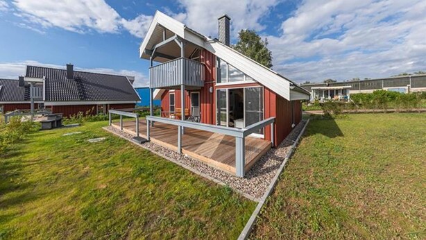 A modern two-story house with a balcony, a wooden deck, and a clear sky. - Ferienhaus im Ferienpark Mueritz (Rechlin)