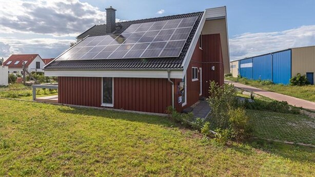 Une maison moderne avec un toit en pente et des panneaux solaires.