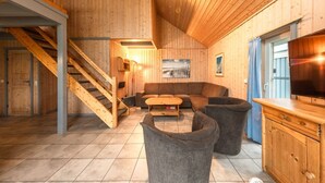 A wooden interior with a staircase, a sofa, a coffee table, and a television. - perfektes Ferienhaus für Familien (Rechlin)