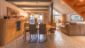 A spacious living area with a dining table and chairs, a sofa, and a wooden ceiling with exposed beams. - exklusives skandinavisches Ferienhaus (Granzow)