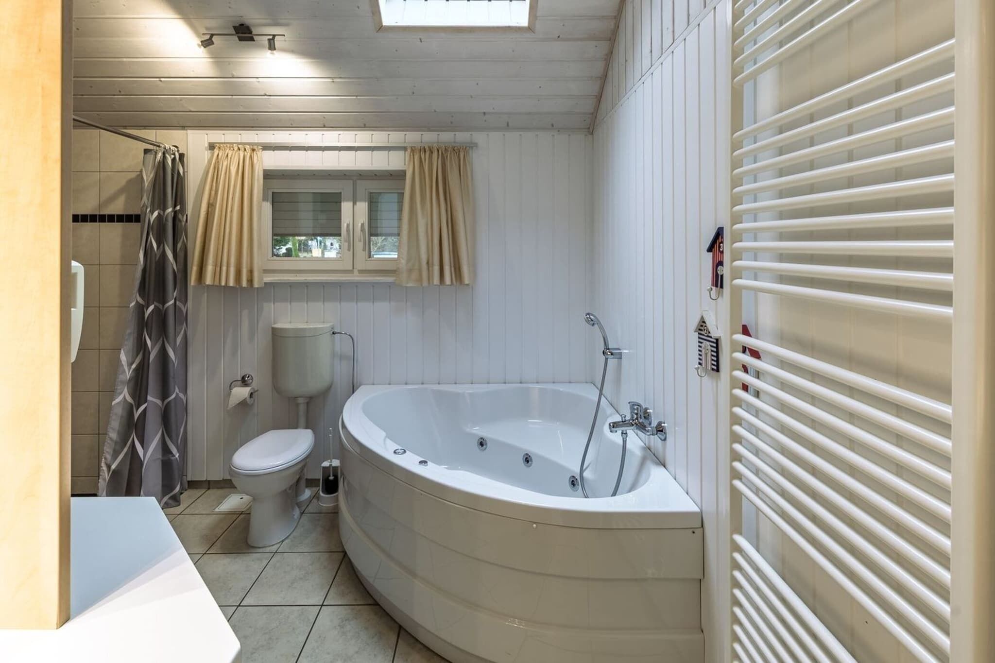 Et badeværelse med badekar, toilet og bruseforhæng.